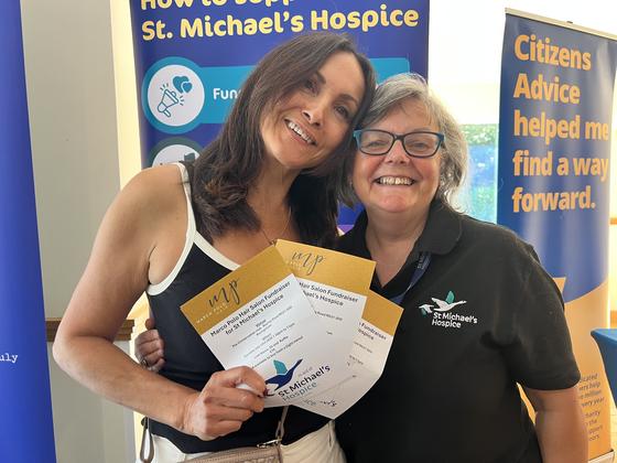 Two members holding raffle prize certificates for St Michael's Hospice