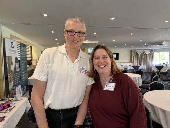 Two members smiling beside the Bowers Broker Services and Digital House banners