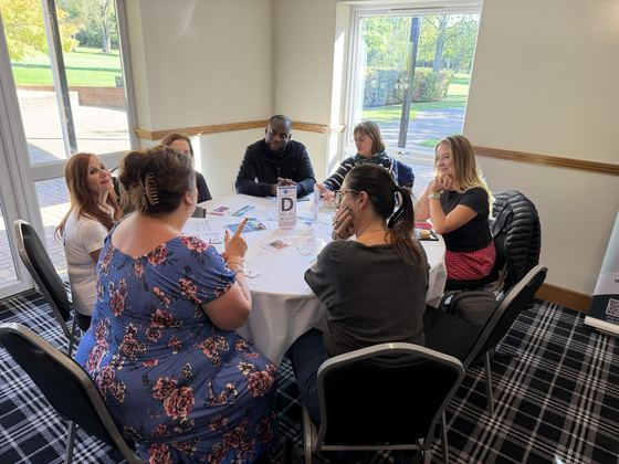 A table of members listening to each other introduce their businesses