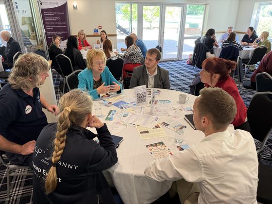 Members swapping ideas around a table by the windows