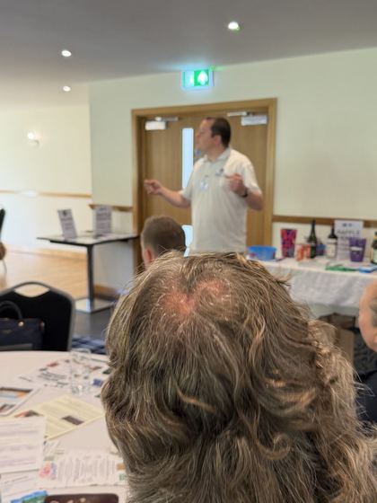 An organiser giving the welcome talk beside the raffle table